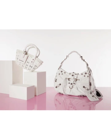 Two white Balenciaga handbags on white pedestals against a white and pink background, showcasing fashion and design elements.