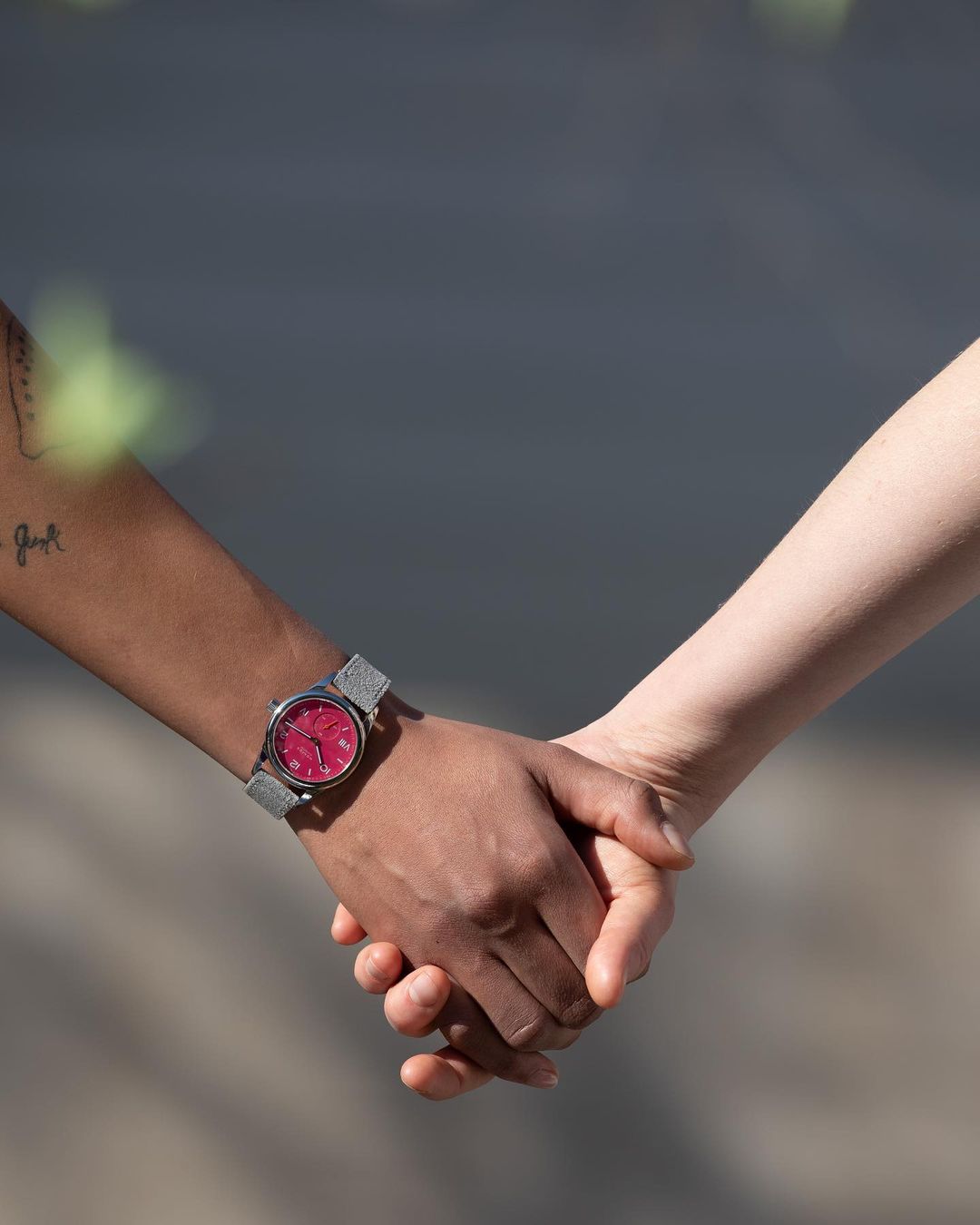 Close-up of two hands intertwined, one with a watch, showcasing a connection and shared moment. Diverse skin tones are visible.