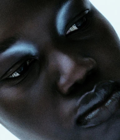 Extreme close-up portrait of a Black model with glossy blue eyeshadow and dark lips captured by Antoine And Charlie