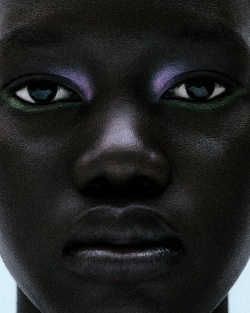 Close-up portrait of a dark-skinned person with colorful makeup on their eyes, set against a pale background in a beauty shot.