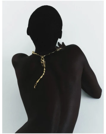 Back view of a person wearing an articulated gold scorpion pendant necklace against a plain white background