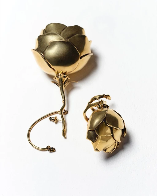 Gold-tone flower shaped statement earrings. The earrings are presented against a white backdrop in an eye-level, medium studio shot.