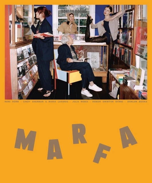 A group of women browse and pose in a bookstore with natural light, surrounded by shelves of books and vintage decor, on a sunny day.