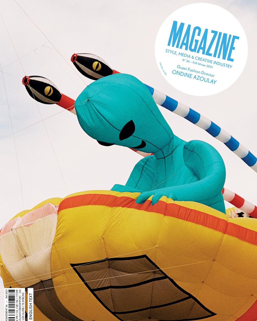 Magazine cover featuring a large, colourful inflatable kite in the shape of an alien and snake with a clear sky background.