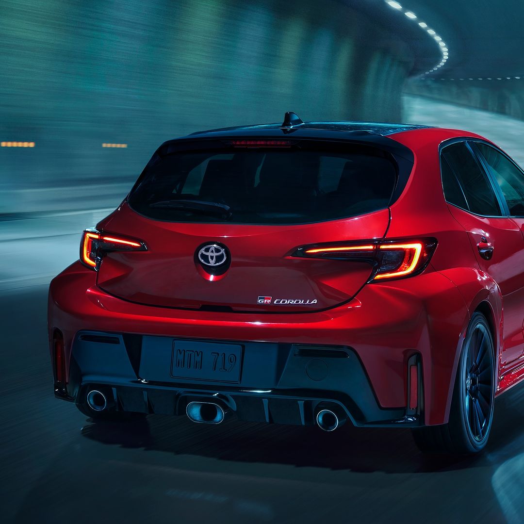 Rear view of a red 2023 Toyota GR Corolla hatchback in a tunnel, showcasing its sporty design and modern taillights.