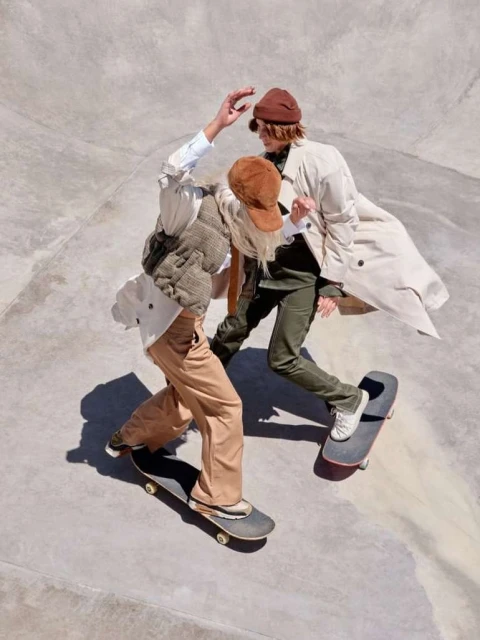 Two young adults in casual fashion on skateboards at a concrete skatepark, capturing a lifestyle and sport blend with a sunny, urban vibe.