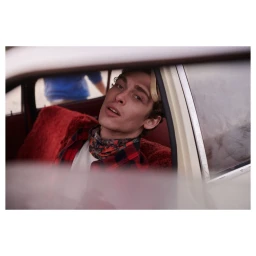 Young man in a red and black plaid shirt seated inside a car, photographed by Antonia Steyn.