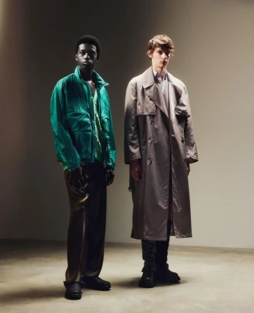 Two male models standing in a studio with green jacket and grey trench coat by Antonio Dicorato