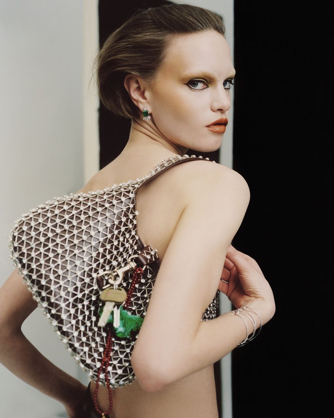 Model wearing a beaded mesh bag with hanging keys and bracelets, captured in a portrait by Antonio Dicorato in Paris.