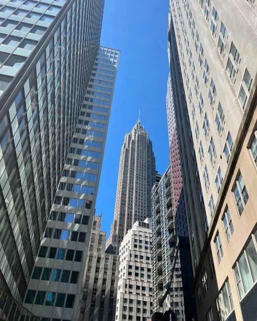 Tall buildings rise to meet a clear blue sky in an urban downtown setting, emphasizing architecture and cityscape.