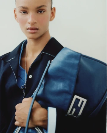 Model wearing dark jacket and blue shirt holding a large blue handbag in Paris by Antonio Dicorato