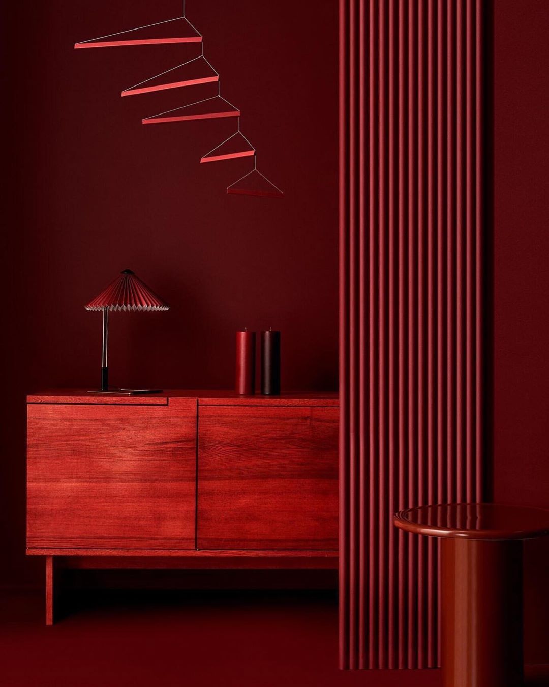Interior design features a monochromatic red room with furniture, including a sideboard, table lamp, decorative sculpture, and red wall panel.