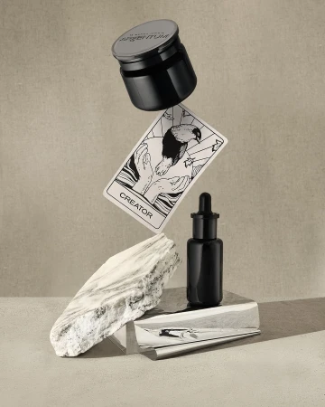 Still life featuring Argentum skincare jar and bottle, creator card, and marble stone, creating a modern and luxurious product shot.