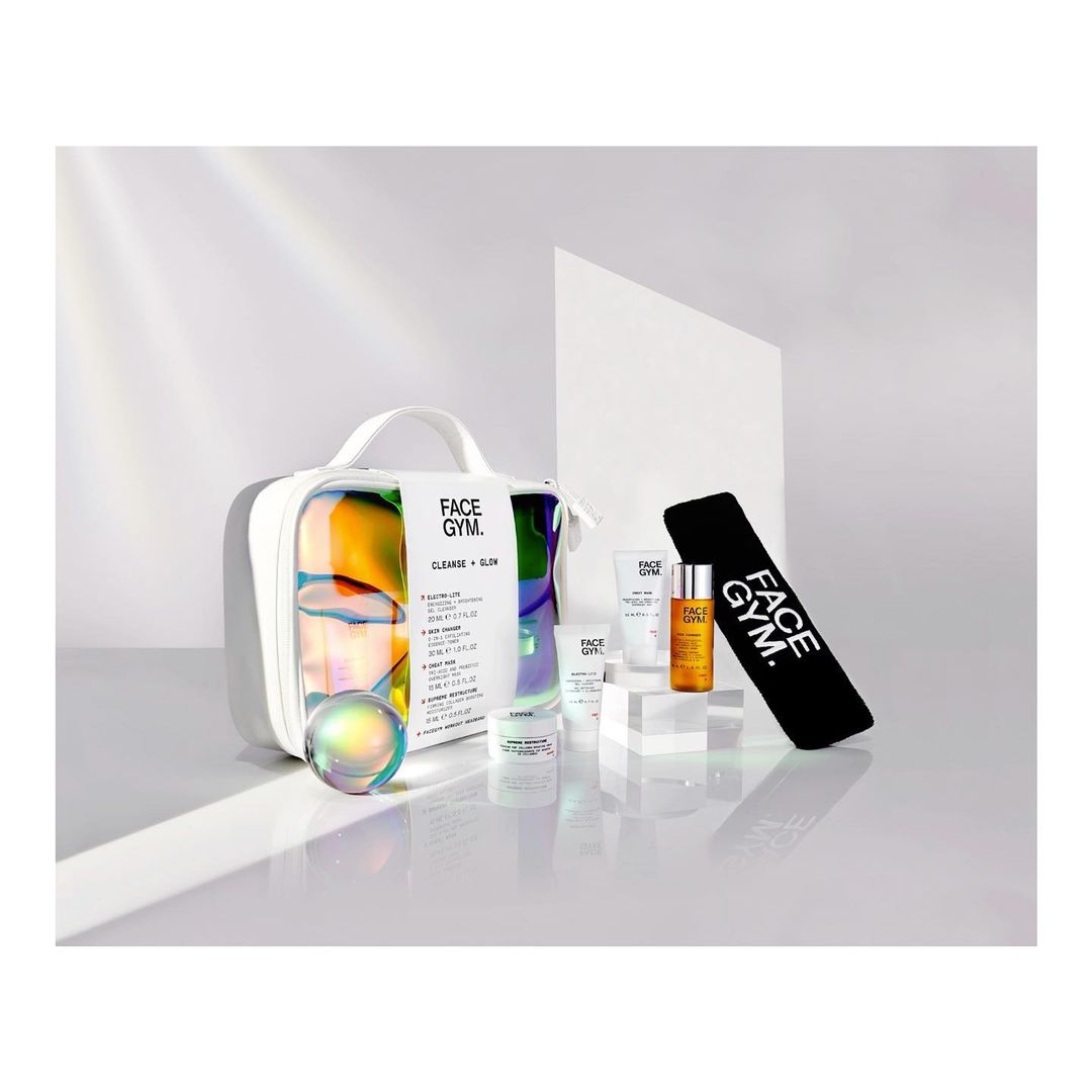 Face Gym skincare product set featuring a bag, orb, and skincare products in white packaging, displayed on a glossy white surface.