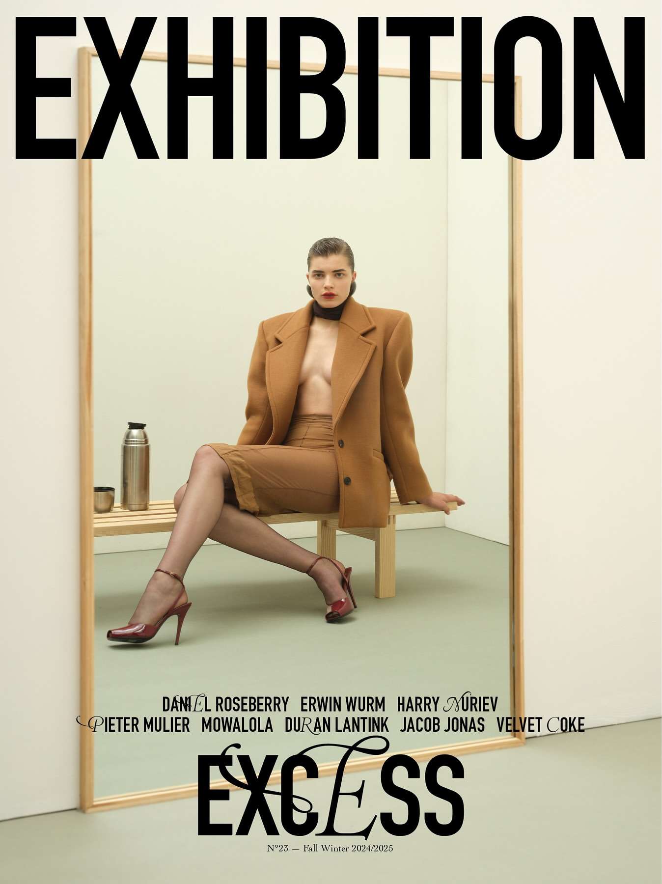 Fashion magazine cover featuring a seated woman in a brown suit reflected in a mirror, with magazine text and exhibition details.