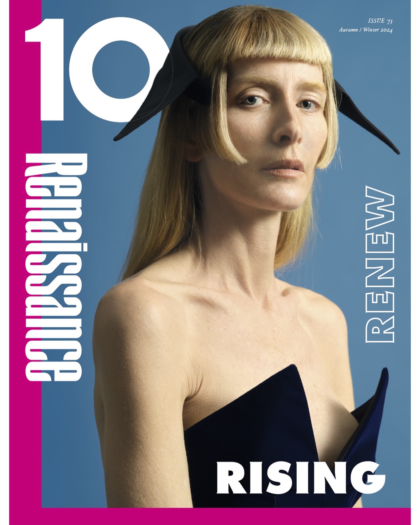 Magazine cover featuring a blonde adult female wearing a black outfit and headpiece against a blue background with white and pink text.