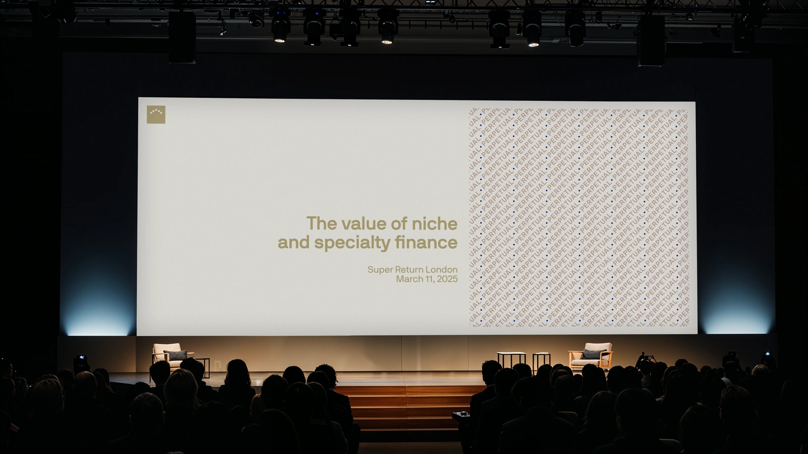 Wide conference stage with a large presentation screen reading The value of niche and specialty finance before a seated audience
