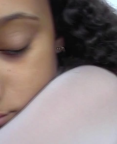 Close-up portrait of a woman with dark curly hair and closed eyes in profile photographed by Anya Holdstock.