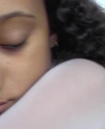 Close-up portrait of a woman with dark curly hair and closed eyes in profile photographed by Anya Holdstock.