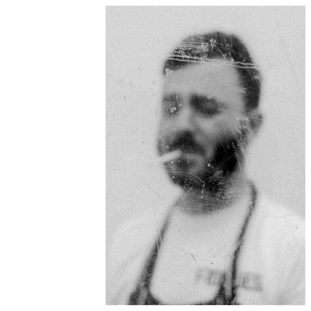 Monochromatic portrait of a bearded man with a cigarette, captured in a blurred, vintage style on a light background with visual wear.