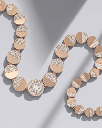 Rose gold diamond necklace arranged in a curved line on a clean grey background with soft shadows