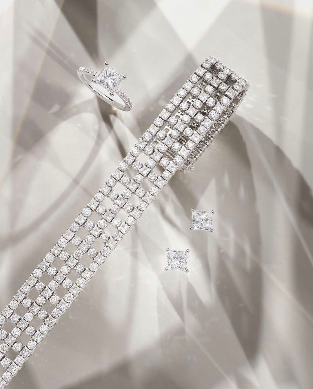 Sparkling diamond jewelry set featuring a bracelet, ring, and stud earrings on a light surface with soft shadows.