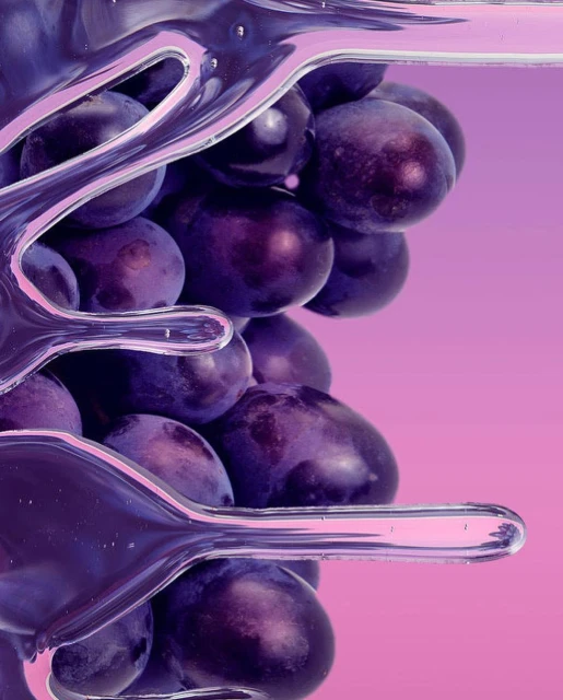 Close-up of fresh dark grapes suspended in clear liquid with light pink backdrop, creating a visually appealing food still life.