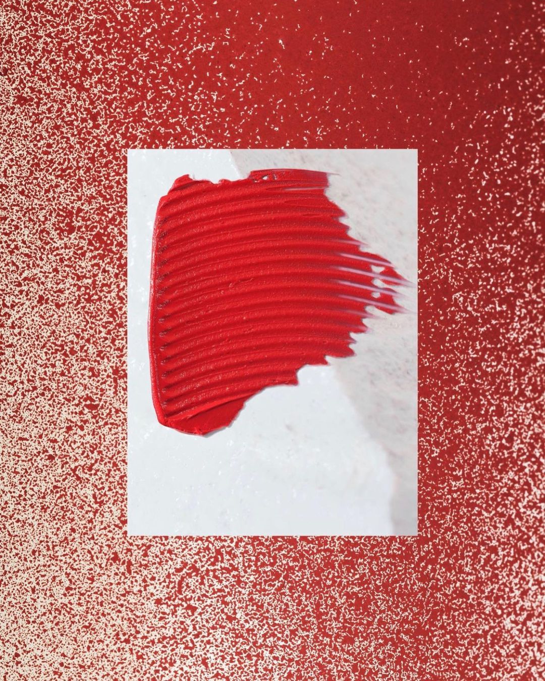 Abstract close-up of a smear of red lip gloss on a white surface against a speckled red backdrop. Cosmetics beauty background.