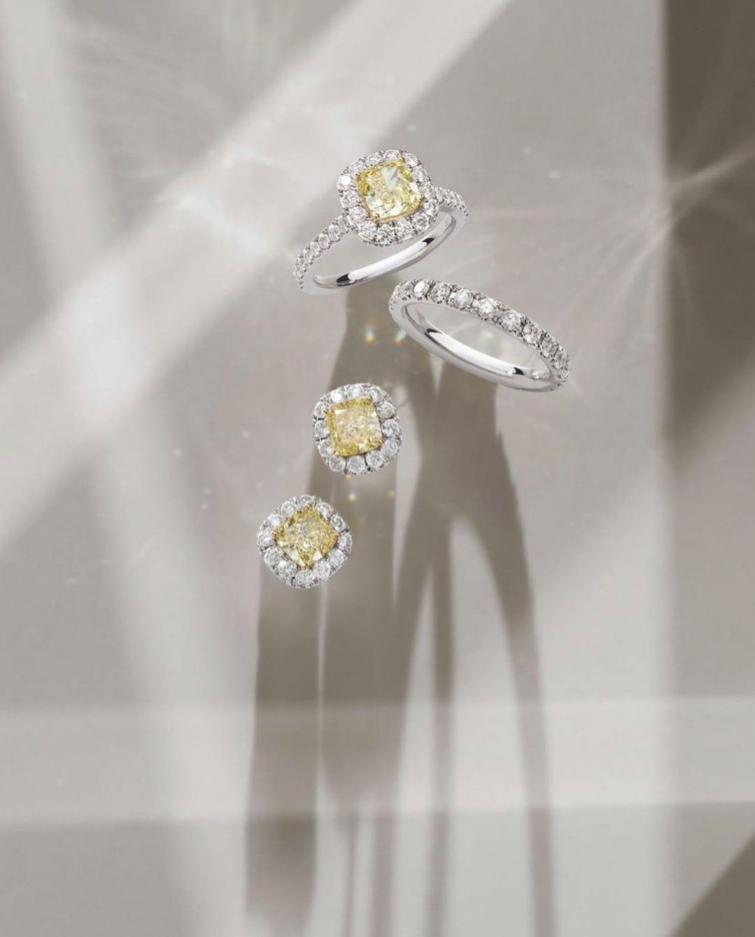 Elegant jewelry still life featuring two diamond rings and diamond earrings, set against a neutral background with soft, filtered light.
