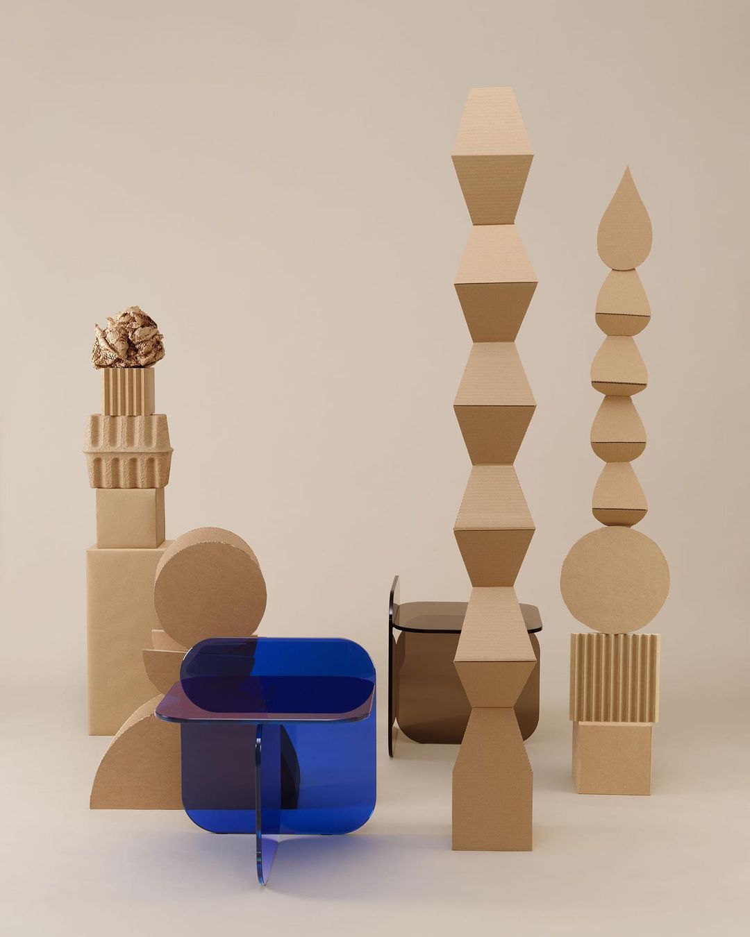 Still life of geometric shapes and a blue acrylic table against a neutral background, showcasing modern design and abstract composition.