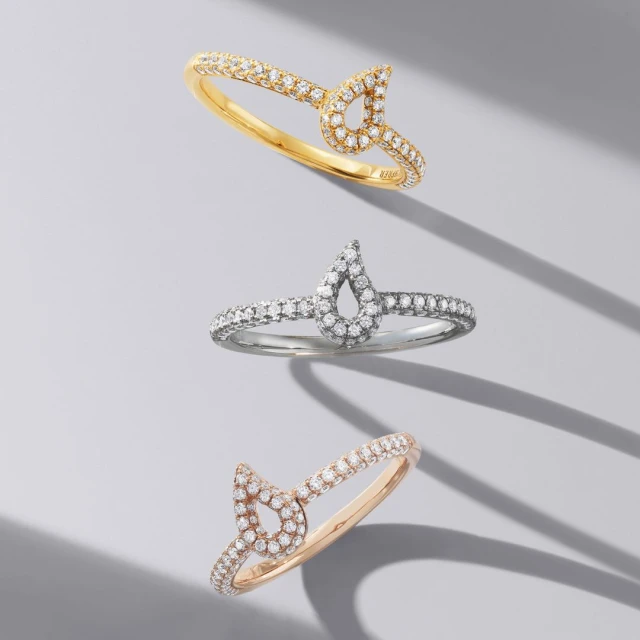 Three rings with diamond accents are displayed on a gray surface with soft shadows, showcasing jewelry for fashion and beauty.