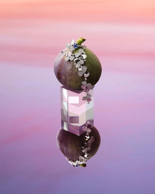 Close-up of a fig adorned with jewelry on a reflective cube. The composition has an ethereal quality, set against a soft gradient backdrop.