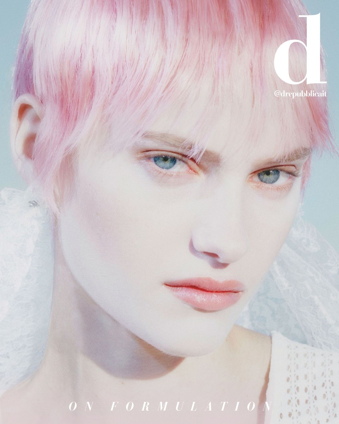 Close-up portrait of a fair-skinned adult female model with pink hair and light eyes in a studio setting with diffused lighting.