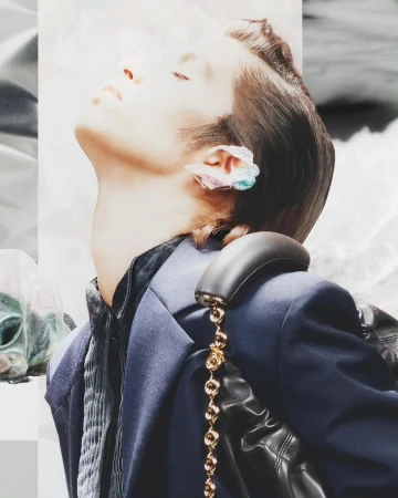 Close-up profile of a person with dark hair tilted back, wearing a dark suit jacket and decorative ear cuff by Arnaud Lajeunie