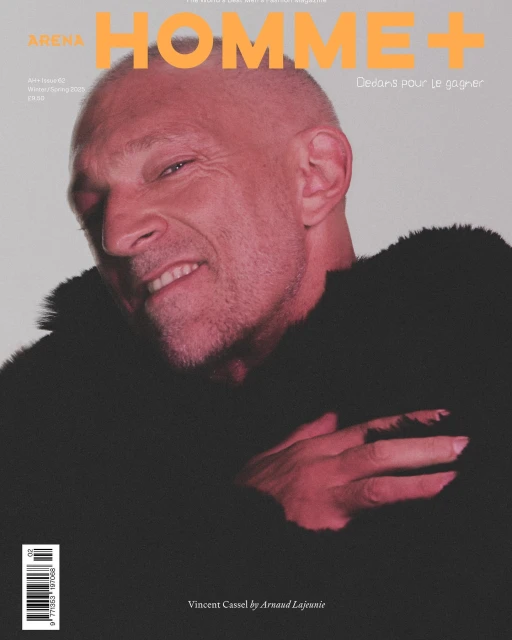 Arena Homme+ magazine cover featuring a close-up of a smiling adult male with short hair and a dark textured jacket against a light background.