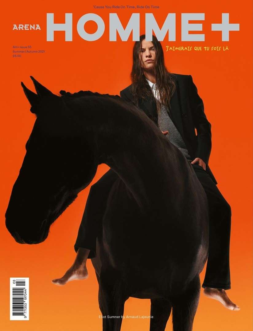 Arena Homme+ cover featuring a long-haired male model in a black suit riding a black horse against a vibrant orange background.