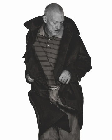 Portrait of Vincent Cassel wearing a dark coat and striped polo shirt by photographer Arnaud Lajeunie in London.