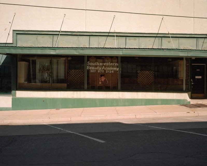 Exterior view of Southwestern Beauty Academy, a storefront business with a graphic on the window and an awning above the entrance.