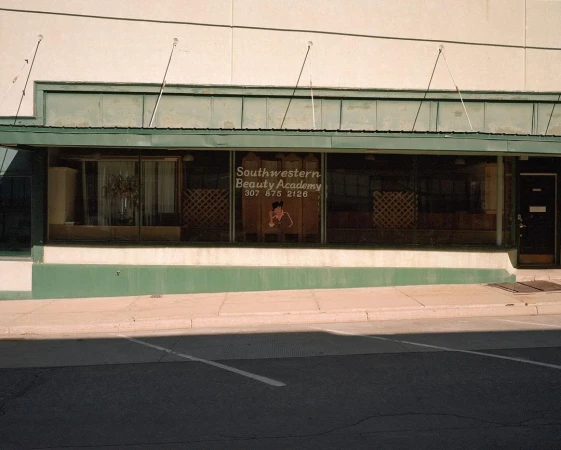 Exterior view of Southwestern Beauty Academy, a storefront business with a graphic on the window and an awning above the entrance.