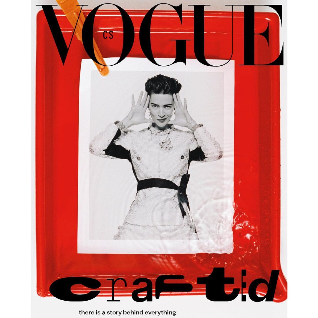 Black and white fashion photo on the cover of Vogue magazine, featuring a woman in an ornate dress, framed by red and orange.