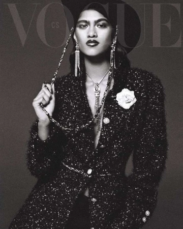 Vogue cover featuring a female model in a black hat and tweed jacket with statement jewelry, posing in a studio setting.