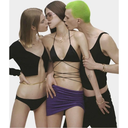 Three models posed closely together against a white background wearing black tops and a purple skirt