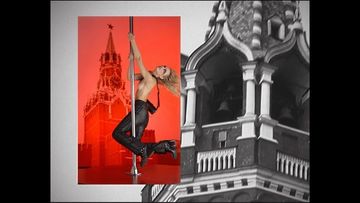 A person pole dancing with Red Square in the background and a black and white structure similar to Red Square on the right.