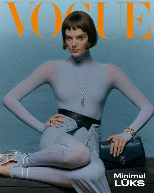 Vogue magazine cover featuring a woman in a light blue bodysuit, posing with a purse against a matching backdrop, striking a confident pose.