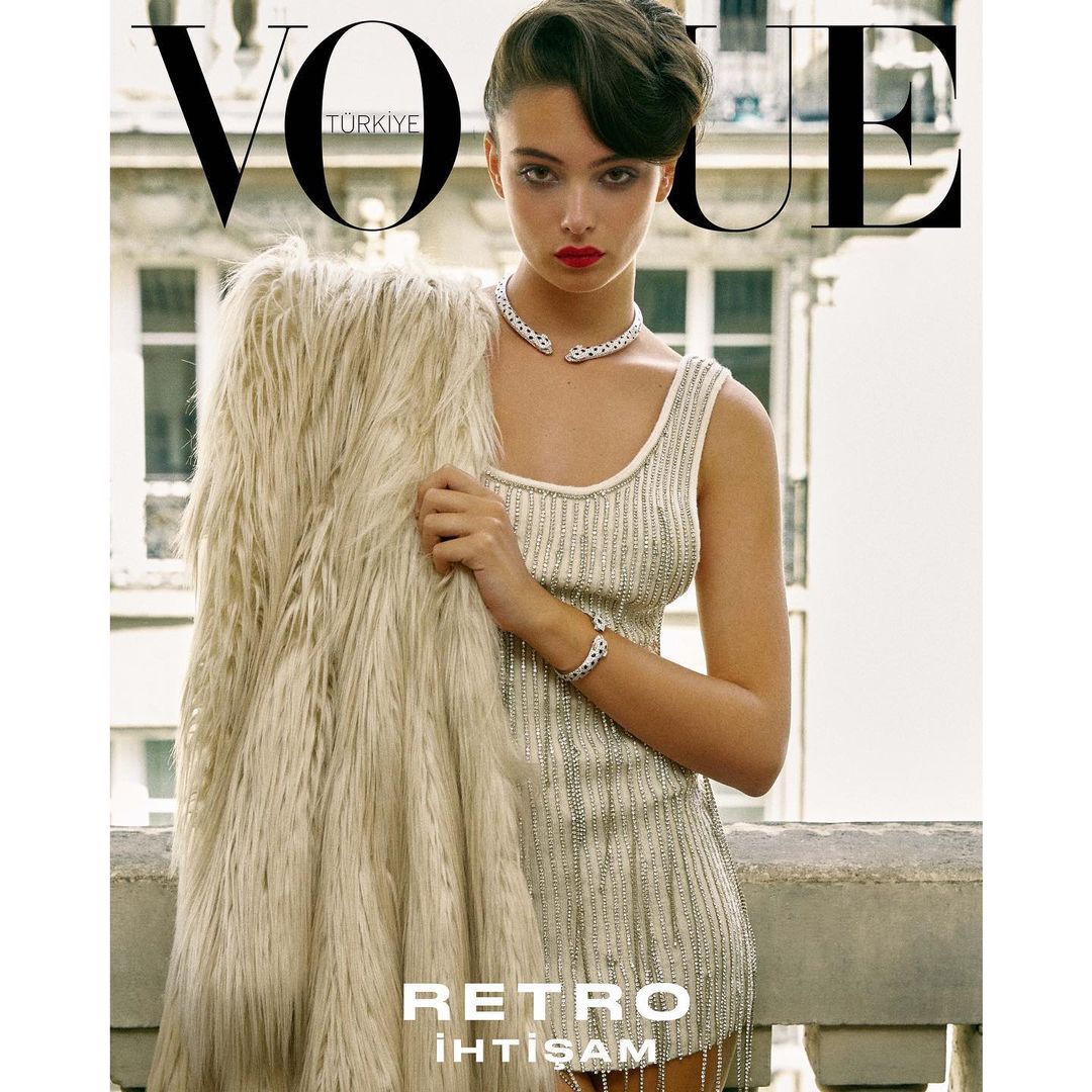 Vogue Turkey cover featuring a stylish young woman in a beaded dress and fur coat, posing on a balcony with city backdrop.