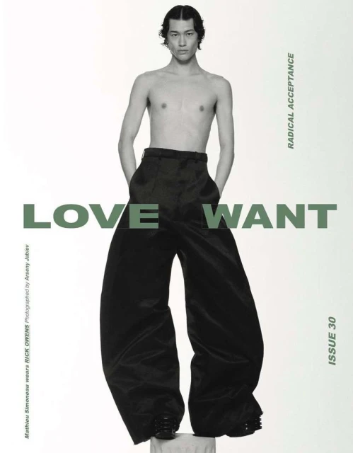 A shirtless male model poses against a white background wearing oversized black pants, showcasing a fashion editorial style.