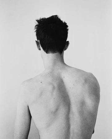 Rear view of a man with dark hair and freckles on his back against a light background by Arthur Delloye