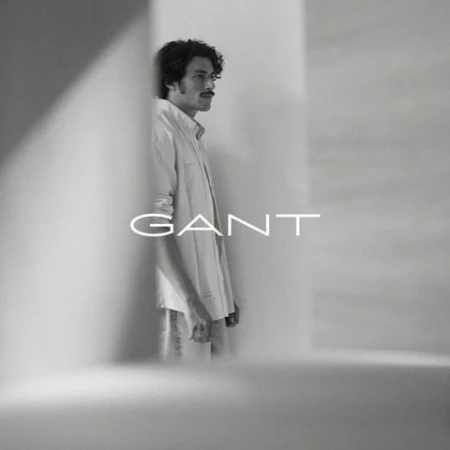 Man with curly hair and a mustache wearing a button-down shirt framed between structural architecture with overlayed text