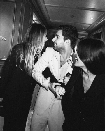 Black and white candid photograph of three young people laughing and interacting inside a hallway in Paris.