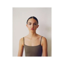 Portrait of a woman wearing a dark olive green spaghetti strap top against a plain white background